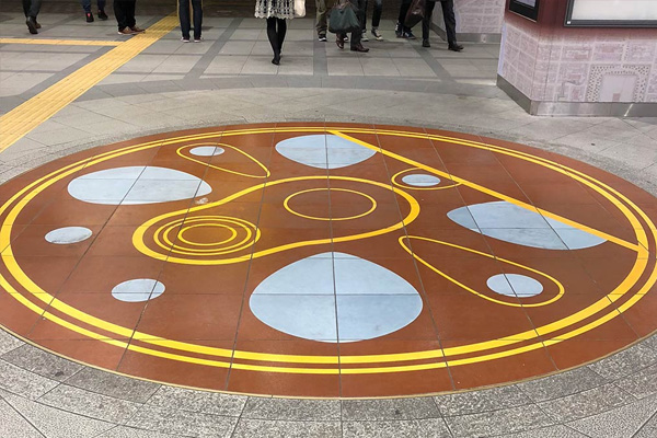 駅構内の改札外に設置した円形の床面グラフィックタイル（横浜市）